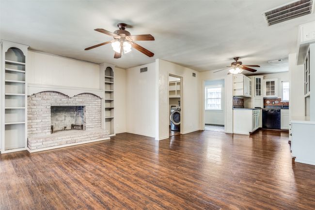 Unfurnished living room featuring a ceiling fan, washer / dryer, a fireplace, and dark wood-type flooring | Image 20