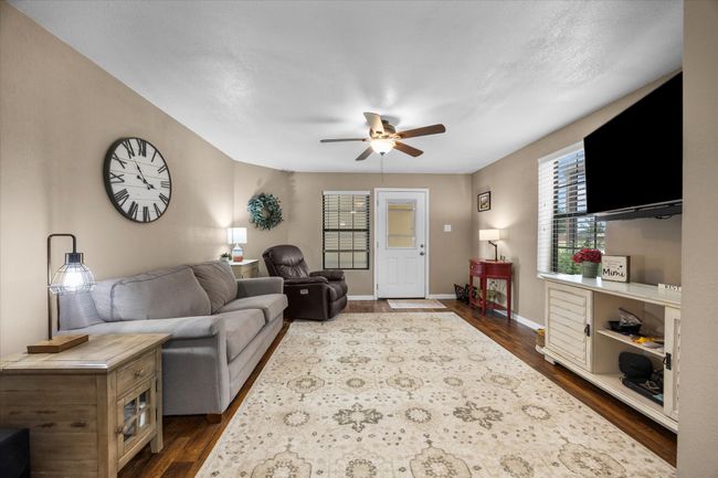 Living room featuring dark wood-type flooring and ceiling fan | Image 12