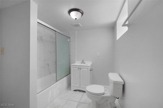 lower level Bathroom with combined bath / shower with glass door, marble finish floor, toilet, vanity, and visible vents | Image 23