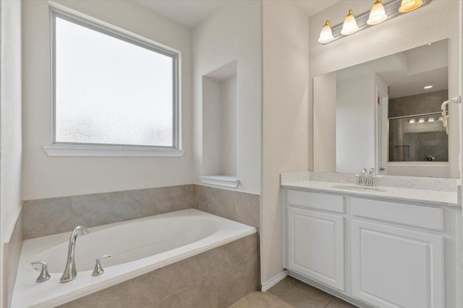 Bathroom with a bath, vanity, light tile patterned floors, and tiled shower | Image 13
