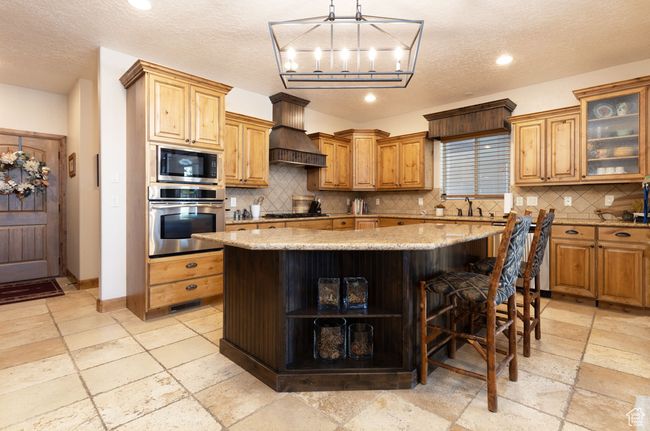 Kitchen featuring oven, premium range hood, stone tile flooring, open shelves, and built in microwave | Image 28