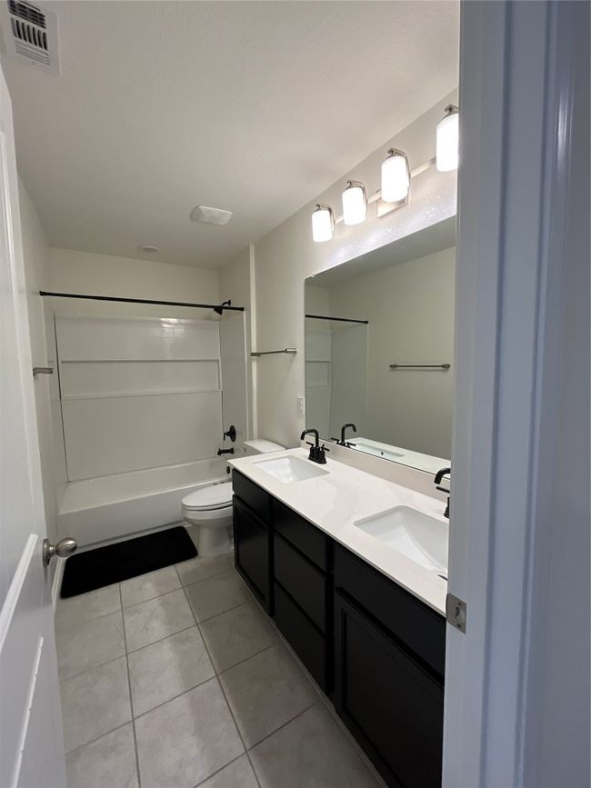 Full bathroom featuring double vanity, visible vents, a sink, tile patterned floors, and toilet | Image 20