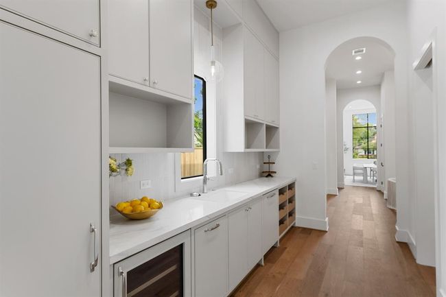 Tucked discreetly behind the main kitchen, the butler’s pantry offers a fully equipped staging space with a wine fridge, undermount sink with glass rinser, second paneled dishwasher, and generous custom cabinetry—perfect for effortless entertaining and everyday prep. | Image 12