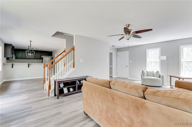 Living room featuring stairway, light wood-style floors, a ceiling fan, and baseboards | Image 4