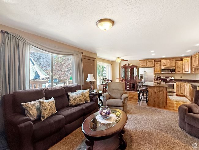 Living area featuring light wood-type flooring, a textured ceiling, ceiling fan, and recessed lighting | Image 4