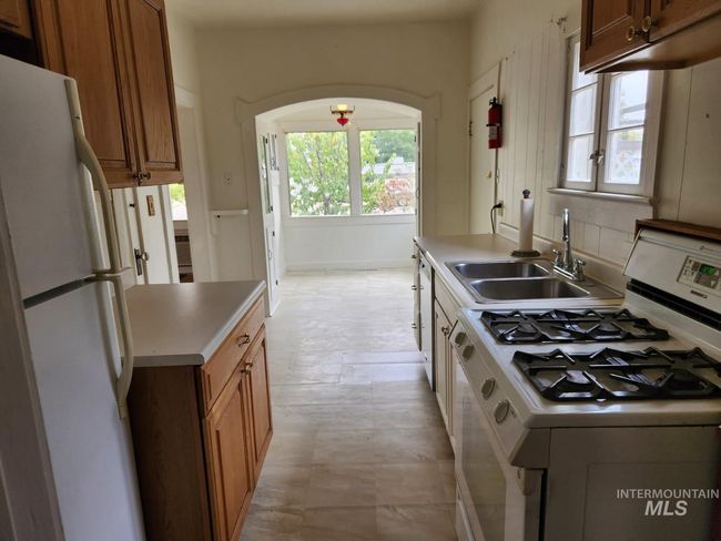 Kitchen featuring white appliances, light countertops, and brown cabinetry | Image 6