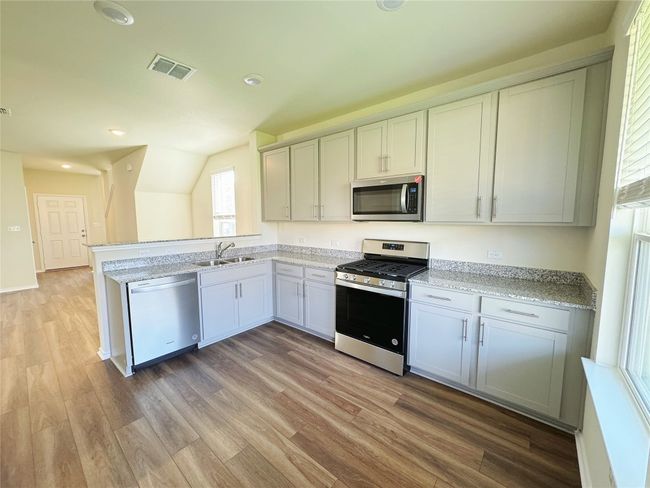 Kitchen featuring appliances with stainless steel finishes, a sink, light wood-style floors, a peninsula, and recessed lighting | Image 5