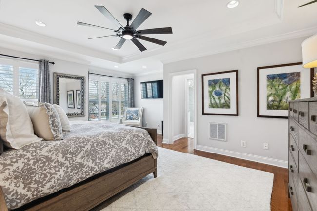 The primary bedroom is spacious and serene with large windows, tray ceiling, and a private sitting area. | Image 17