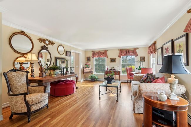 Living room with a baseboard radiator, ornamental molding, and wood finished floors | Image 7