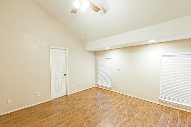 Spare room with wood finished floors, vaulted ceiling, and a ceiling fan | Image 16