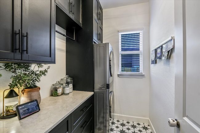Laundry area with cabinet space, baseboards, stacked washer / dryer, and light floors | Image 14