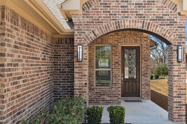 View of exterior entry featuring brick siding and a shingled roof | Image 5