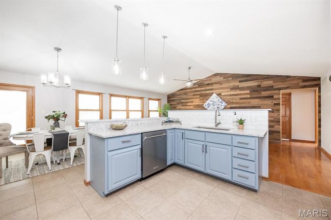 Kitchen featuring dishwasher, a sink, wooden walls, vaulted ceiling, and a chandelier | Image 20