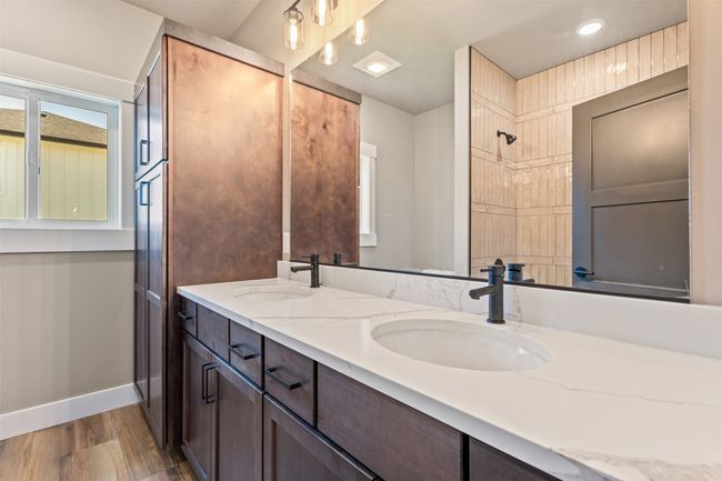 Bathroom featuring double vanity, baseboards, wood finished floors, and a shower | Image 24