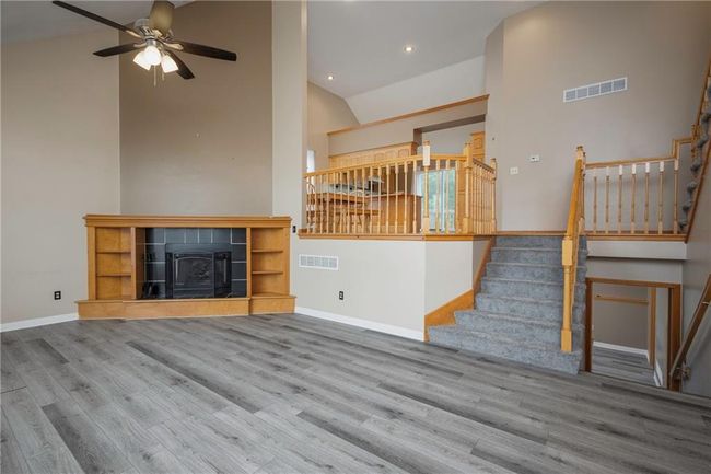 Unfurnished living room with wood finished floors, stairs, a ceiling fan, baseboards, and recessed lighting | Image 7