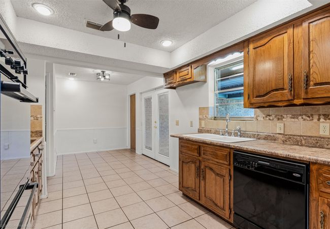 Kitchen featuring dishwasher, a sink, a textured ceiling, and brown cabinetry | Image 10