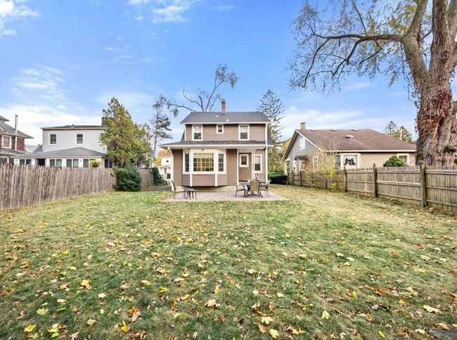 Rear view of house featuring a patio, a chimney, a fenced backyard, and a lawn | Image 9