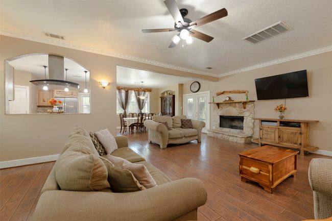 Living area with a ceiling fan, hardwood / wood-style floors, baseboards, arched walkways, and a stone fireplace | Image 4