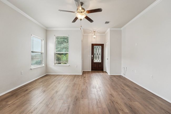 Foyer featuring a ceiling fan, wood finished floors, ornamental molding, and baseboards | Image 8