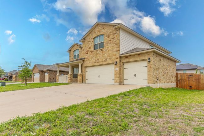 Traditional-style house featuring fence, an attached garage, stone siding, a front yard, and concrete driveway | Image 33