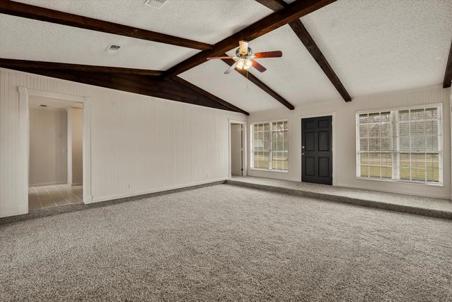 Spare room with lofted ceiling with beams, ceiling fan, carpet flooring, and a textured ceiling | Image 8