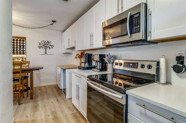 Kitchen with light countertops, light wood-type flooring, appliances with stainless steel finishes, and white cabinetry | Image 7