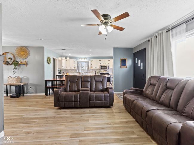 living room featuring baseboards, a textured ceiling, light wood-style flooring, and a ceiling fan | Image 8