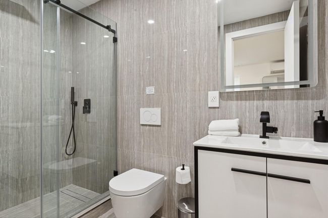 Full bathroom featuring tile walls, toilet, vanity, and a shower stall | Image 24