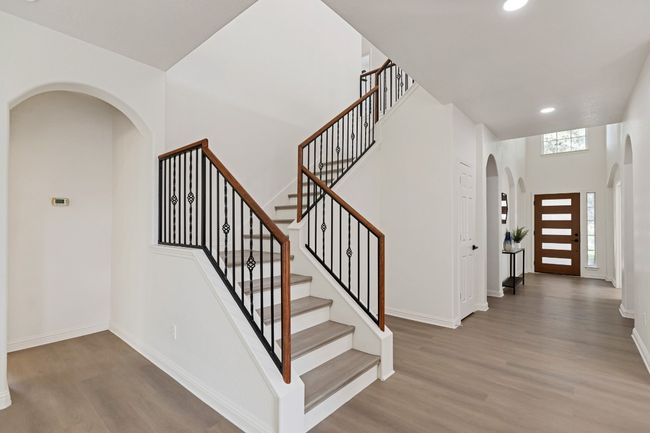 Stairway with arched walkways, wood finished floors, recessed lighting, and a high ceiling | Image 12
