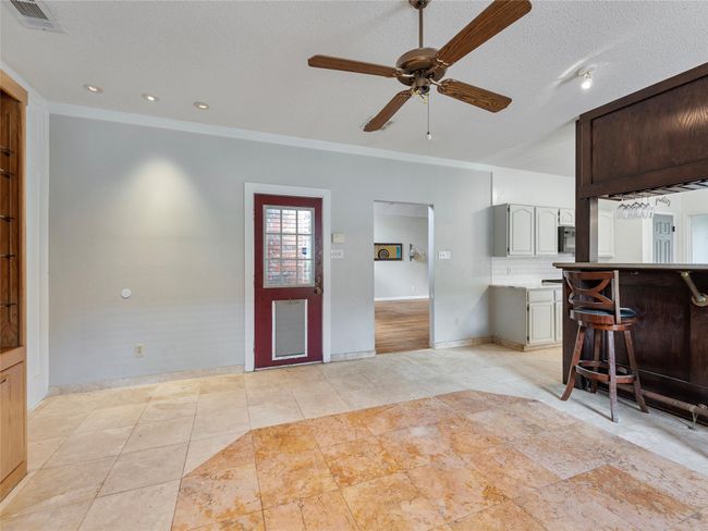 Kitchen featuring a ceiling fan, light countertops, tasteful backsplash, light tile patterned flooring, and a textured ceiling | Image 14