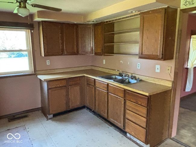 kitchen with ceiling fan, open shelves, visible vents, a sink, and brown cabinets | Image 9