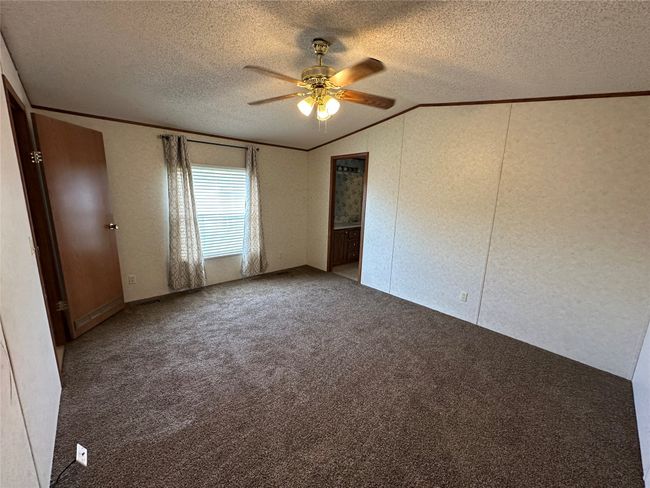 Unfurnished bedroom featuring vaulted ceiling, crown molding, carpet, a textured ceiling, and a ceiling fan | Image 18