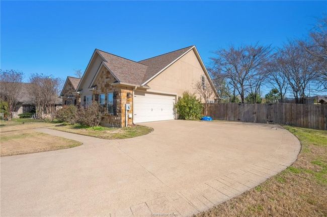 View of side of home with stone siding, driveway, and a garage | Image 4