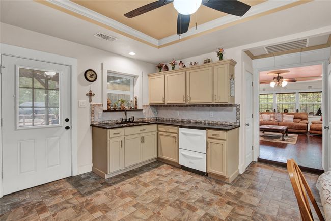Just off the living area, you will see the kitchen. Note the double dishwasher. This area has full-sized eat-in breakfast area. The door at the left leads you to the outdoor back patio area. | Image 12
