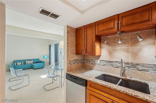 Kitchen featuring brown cabinets, dishwasher, light tile patterned floors, and light stone counters | Image 15