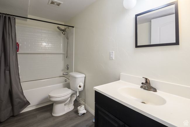 Full bath with wood finished floors, visible vents, toilet, vanity, and shower / tub combo with curtain | Image 21