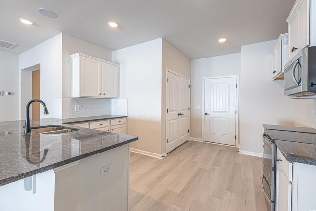 Kitchen featuring dark stone countertops, visible vents, a peninsula, a sink, and appliances with stainless steel finishes | Image 25