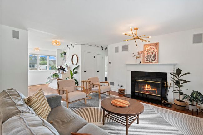 Living room with wood finished floors, a chandelier, and a glass covered fireplace | Image 5