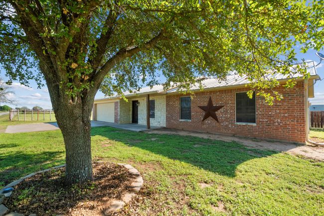 Ranch-style home with an attached garage, driveway, brick siding, and a metal roof | Image 5