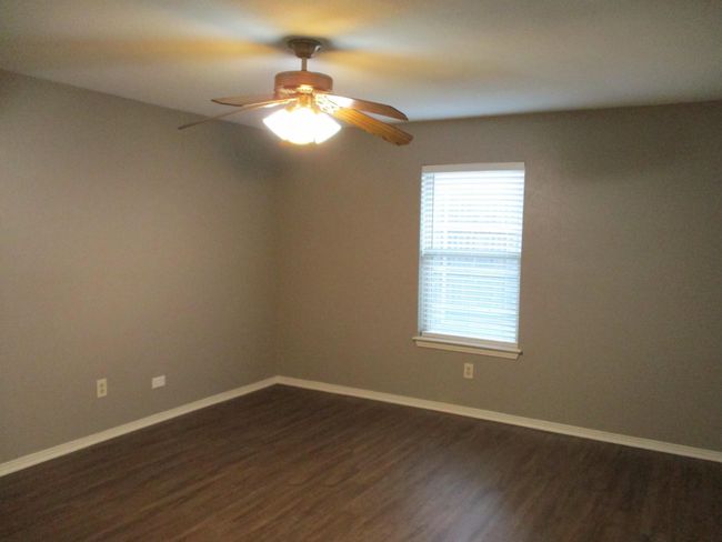Main bedroom featuring dark wood look vinyl plank flooring, ceiling fan | Image 6