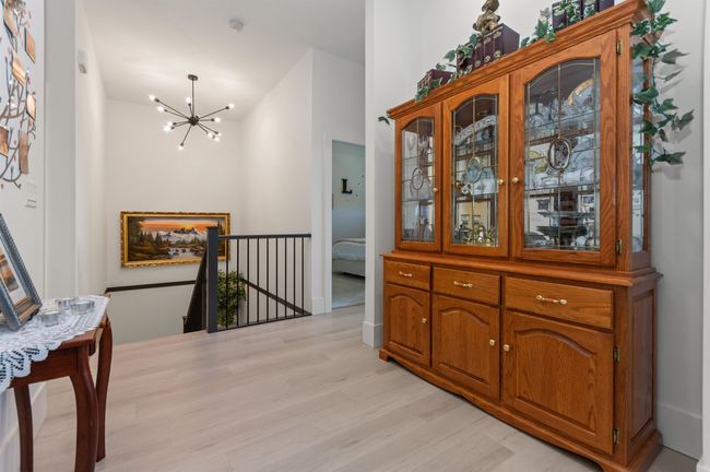 Hall featuring a chandelier, light wood finished floors, and an upstairs landing | Image 14