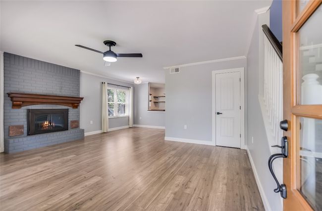 Unfurnished living room with ceiling fan, wood finished floors, ornamental molding, and a fireplace | Image 5