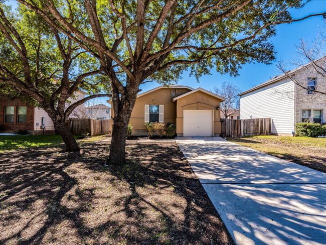The home’s curb appeal includes a stucco exterior, shade trees, single-car garage, and a long, level driveway. | Image 6