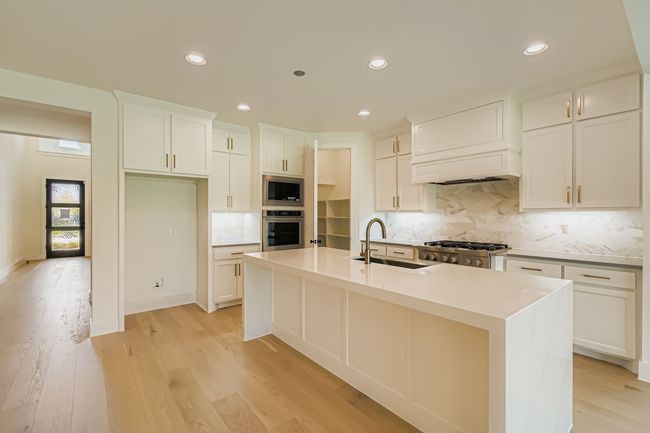 Kitchen with decorative backsplash, light stone counters, recessed lighting, light wood-style floors, and appliances with stainless steel finishes | Image 10