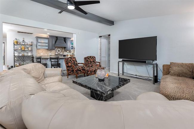 Carpeted living room featuring ceiling fan, sink, and lofted ceiling with beams | Image 9