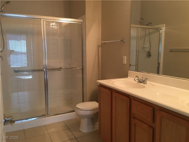 Bathroom featuring a shower stall, tile patterned floors, double vanity, and toilet | Image 7