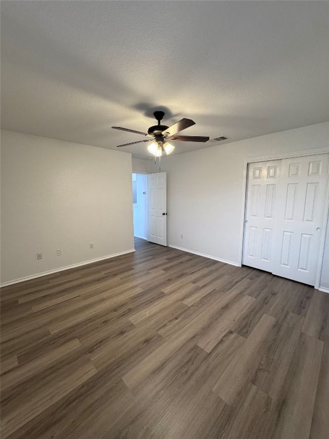 Unfurnished bedroom featuring dark wood-style flooring, ceiling fan, and a closet | Image 26