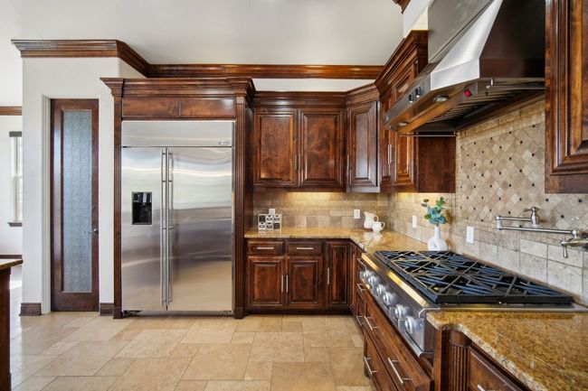 Kitchen with light stone counters, backsplash, stainless steel appliances, and wall chimney exhaust hood | Image 17