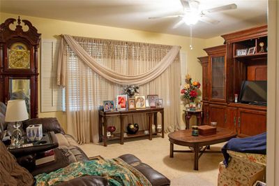 Living area with ceiling fan and light colored carpet | Image 2