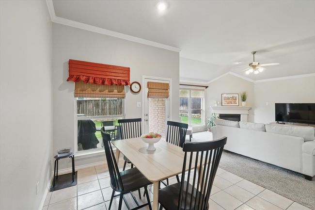 Dining room with crown molding, a ceiling fan, light tile patterned floors, and a fireplace | Image 16